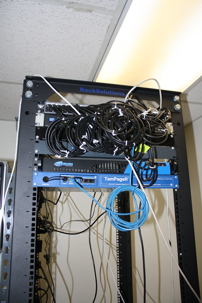 Small wall rack with coiled cables and a network switch