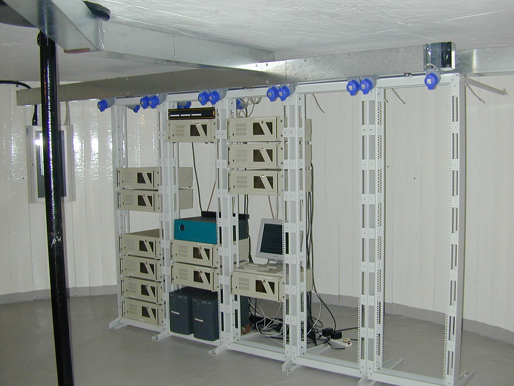 White room with open rack frames holding small equipment units